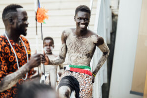 A young African man in cultural dress preparing to perform at the festival
